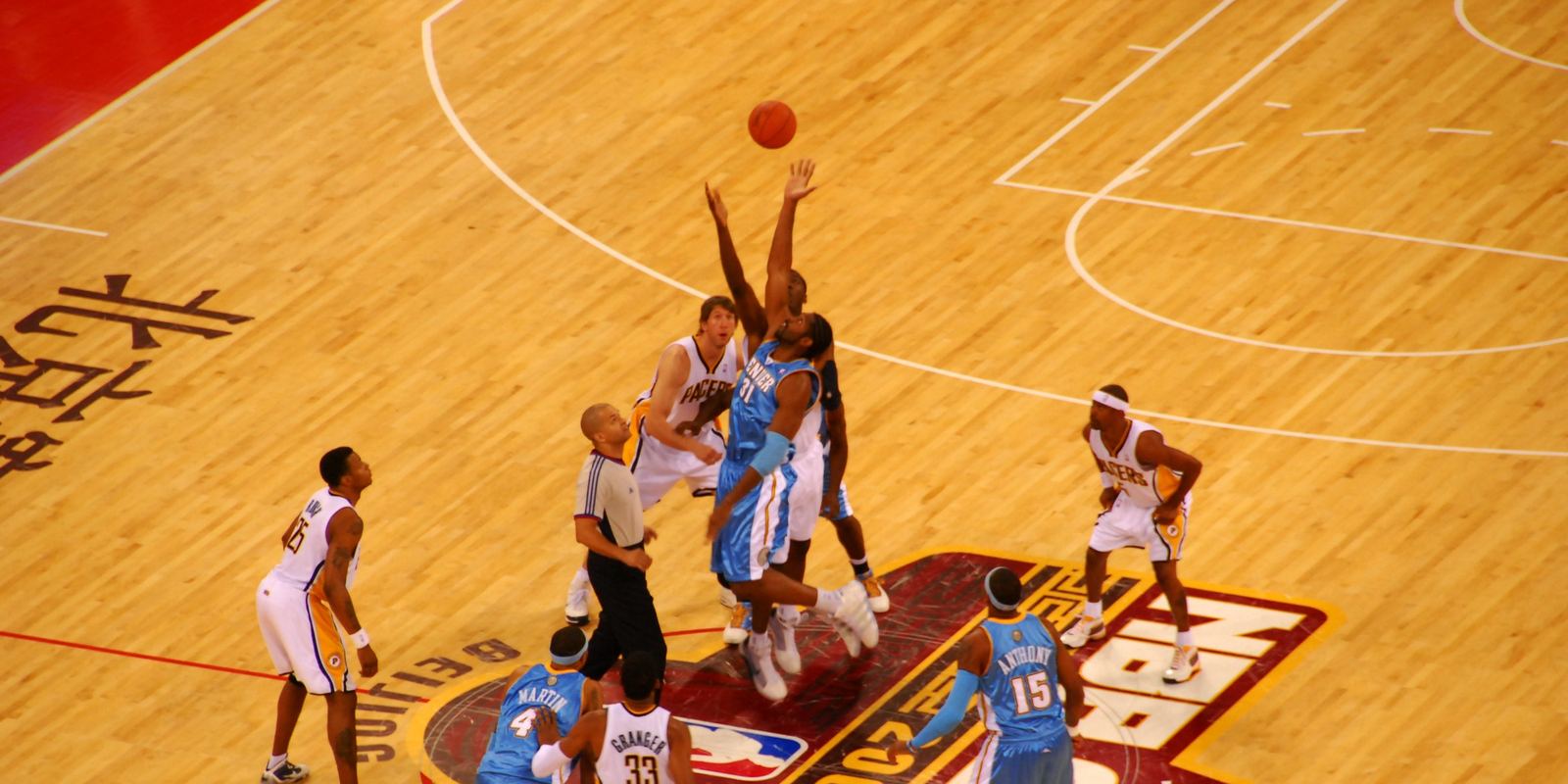 An overhead view of the opening tip with ten players spread around the center circle