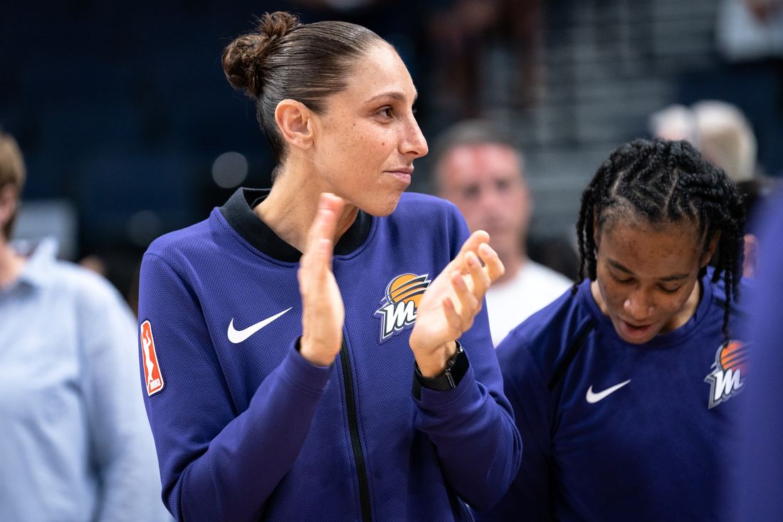 Diana Taurasi clapping on the sideline in a Mercury warmup top
