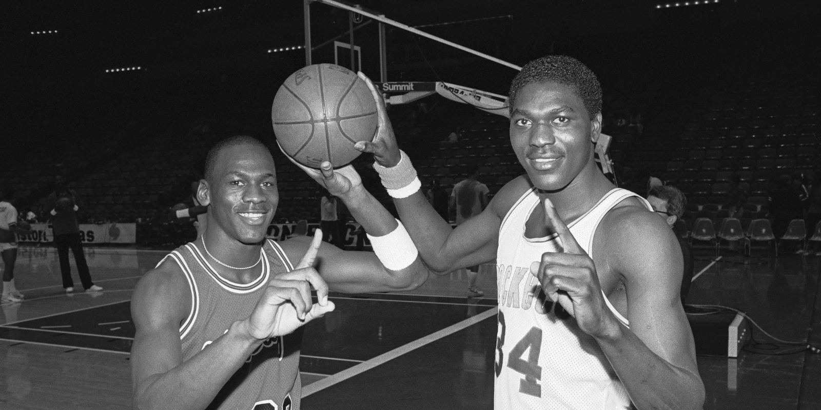 Michael Jordan and Hakeem Olajuwon posing together on a court in the 1980s