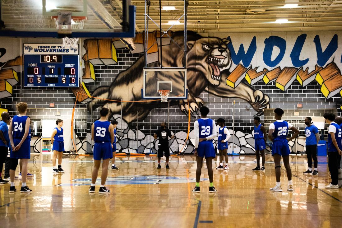 High school players practicing shots at different baskets in a gym