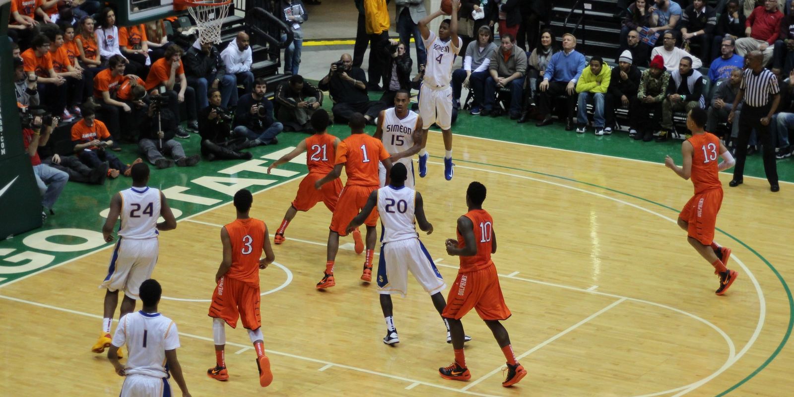 A high school player rising for a jump shot in a packed gym