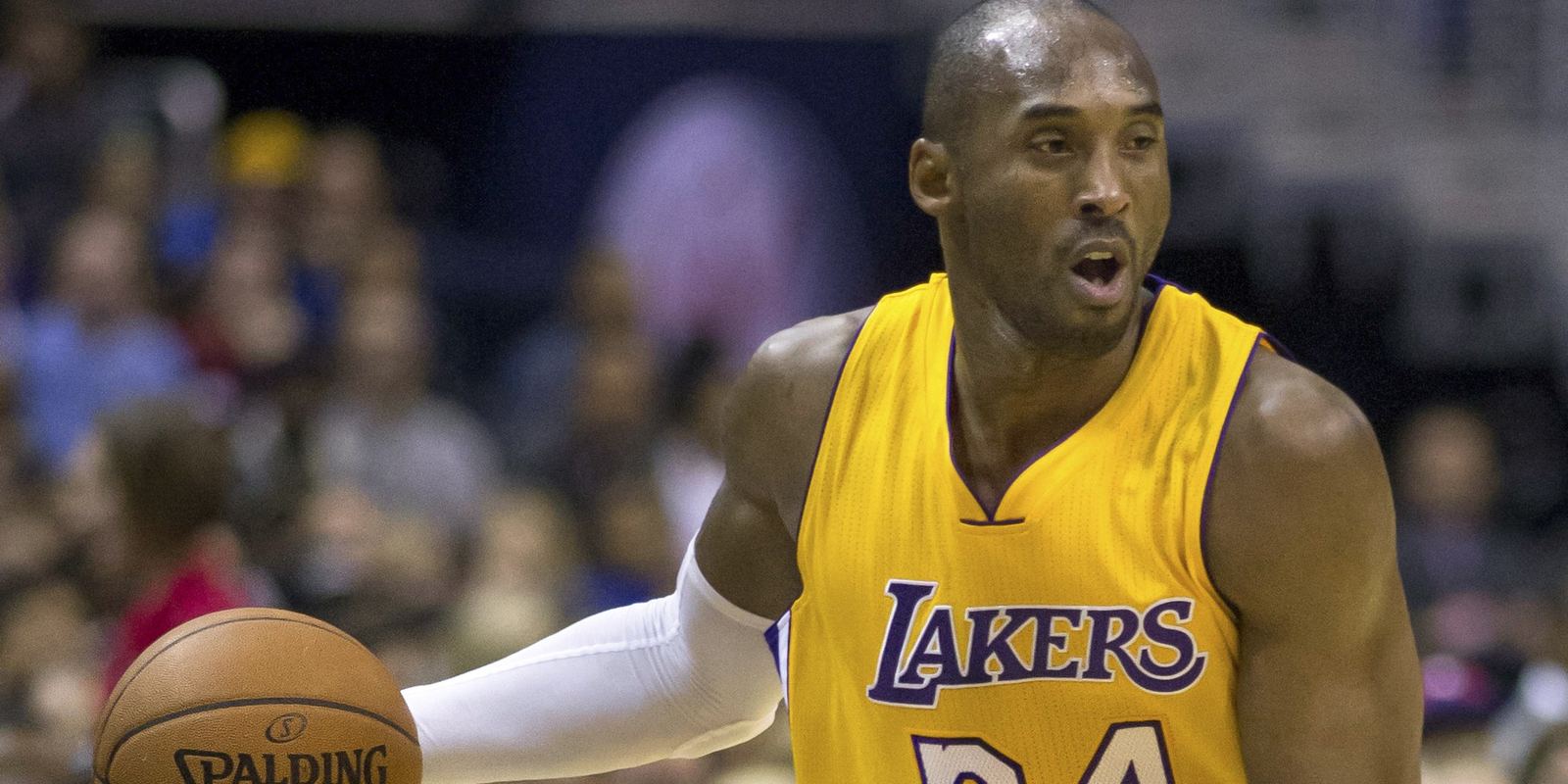 Kobe Bryant bringing the ball up in a gold Lakers number 24 jersey